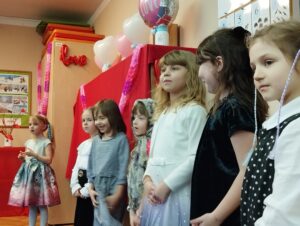 Dzieci ustawione w rzędzie śpiewają piosenkę