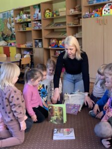 Pani bibliotekarka ustawia ksiązki przed dziećmi