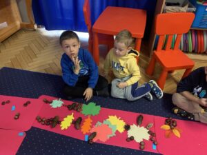 Dzieci układają obrazki z liści szyszek kasztanów