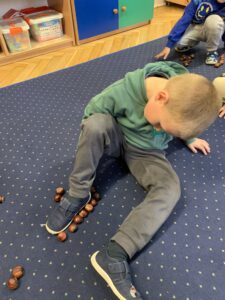 Dziecko układa kasztany obok stopy