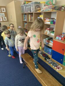dziewczynka idzie po ławeczce do ćwiczeń